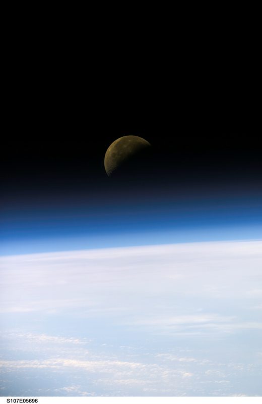 Half moon setting below the Earth's limb as viewed from Space Shuttle Columbia